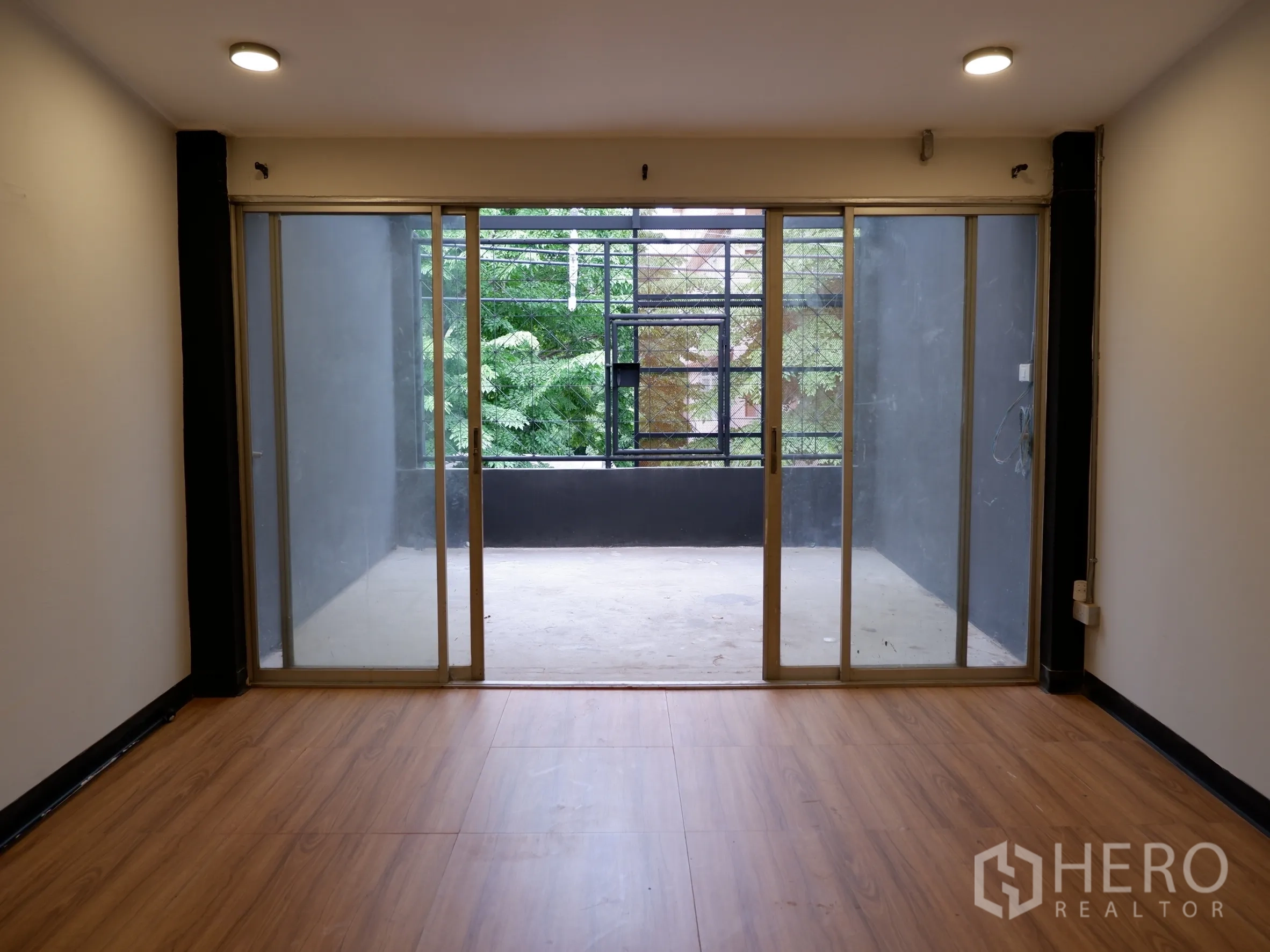 Home Office for sale in Bang Rak, Bangkok - Upper-floor room leading to a covered balcony through large sliding doors, overlooking greenery.