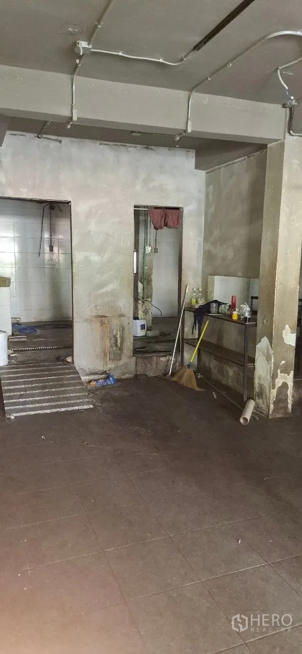 Shophouse for rent or sale in Watthana, Bangkok - Service zone with sinks, tiled wet area, and cleaning tools in an unfinished interior.