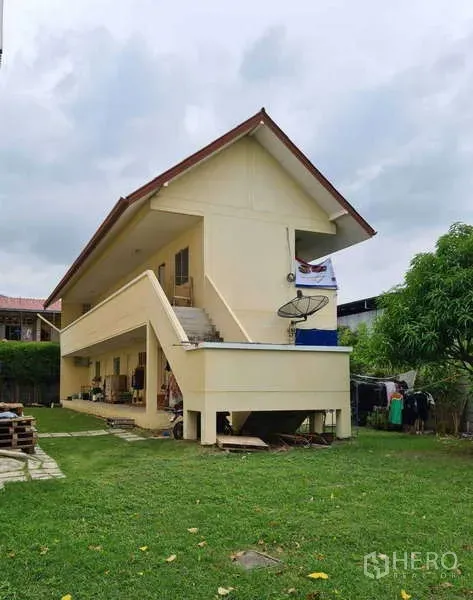 Warehouse for sale in Bang Phli, Samut Prakan - Two-storey staff quarters with an external staircase beside a green lawn in the industrial site.
