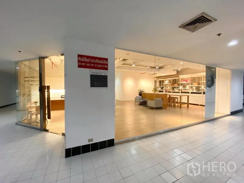 Office Space for rent in Bangkok - Hallway view of a corner glass-fronted office with wood flooring and a bright showroom-style interior.