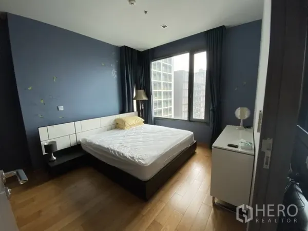 Condominium for rent in Khlong Toei, Bangkok - Cozy bedroom with double bed, wooden floor and large window overlooking city buildings