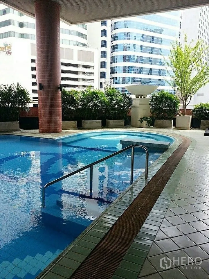 Condominium for rent in Khlong Toei, Bangkok - Condominium swimming pool with city high-rise backdrop and planter greenery.