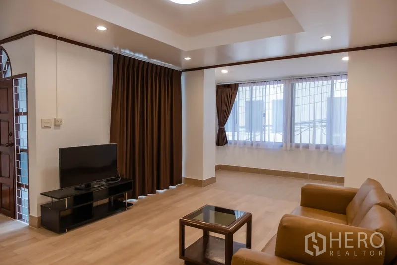 带办公室的家 出租在Khlong Toei, Bangkok - 宽敞客厅，沙发、电视柜与大窗帘。