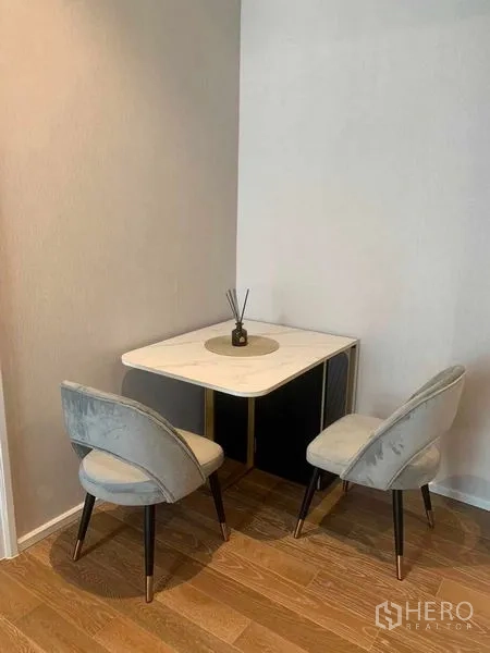 Condominium for rent in Pathum Wan, Bangkok - Compact dining corner with marble‑top table and two upholstered chairs in a stylish condo.