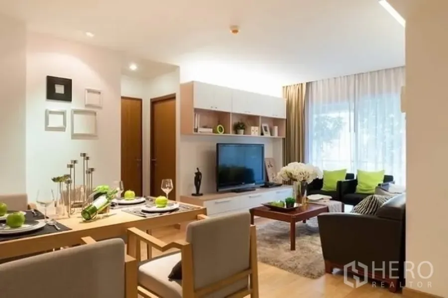 Condominium for rent or sale in Phra Khanong, Bangkok - Bright open-plan living and dining area with TV console, set dining table, and large window with sheer curtains.