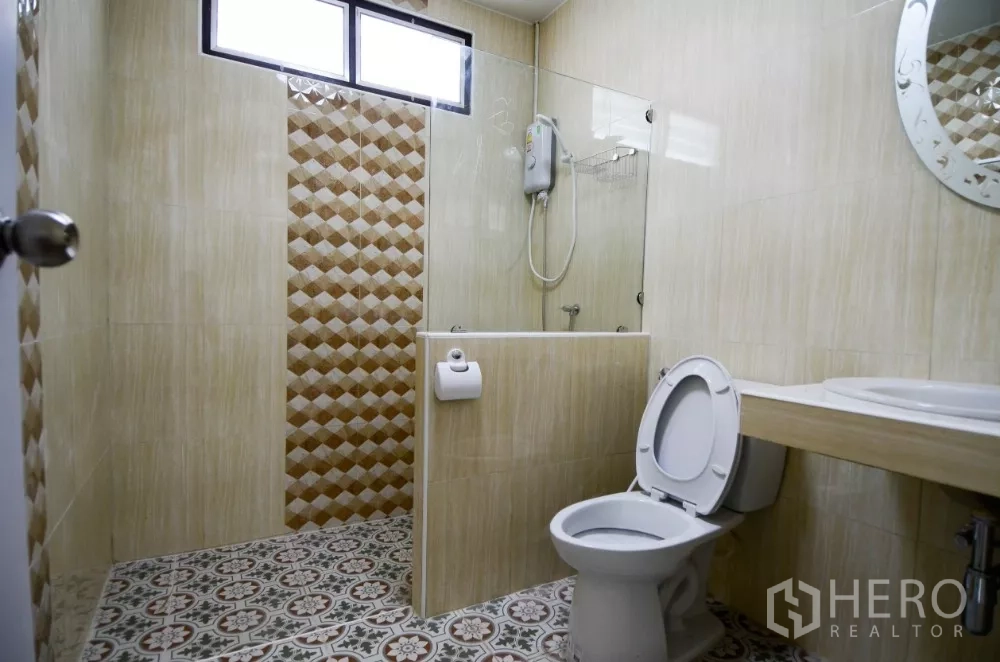 Home Office for rent in Lat Phrao, Bangkok - Bathroom with glass shower screen, water heater and beige wall tiles.