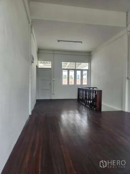 Shophouse for rent in Khlong Toei, Bangkok - Upper floor room with wooden flooring and windowed wall.