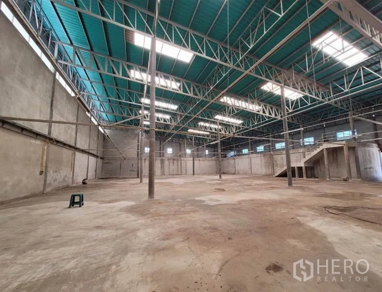 Warehouse for rent or sale in Sai Noi, Nonthaburi - Expansive open warehouse floor with high clear height, skylights, and steel truss structure.