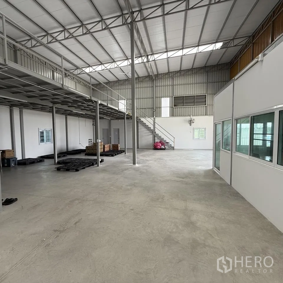 Warehouse for rent or sale in Khlong Luang, Pathum Thani - Open warehouse floor with mezzanine, stair access and office partition.