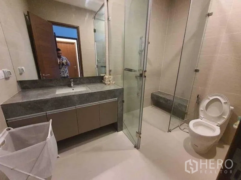 Detached House for rent or sale in Prawet, Bangkok - Neutral-tone bathroom with glass shower enclosure and vanity.