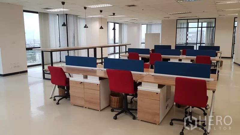 Office Space for rent in Din Daeng, Bangkok - Open-plan workspace with long bench desks, red chairs and pendant lights by wraparound windows.