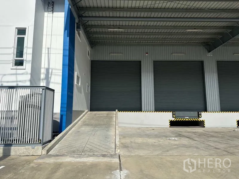Factory for rent in Bang Sao Thong, Samut Prakan - Ramp to loading dock with covered bay and closed roller doors for truck access.
