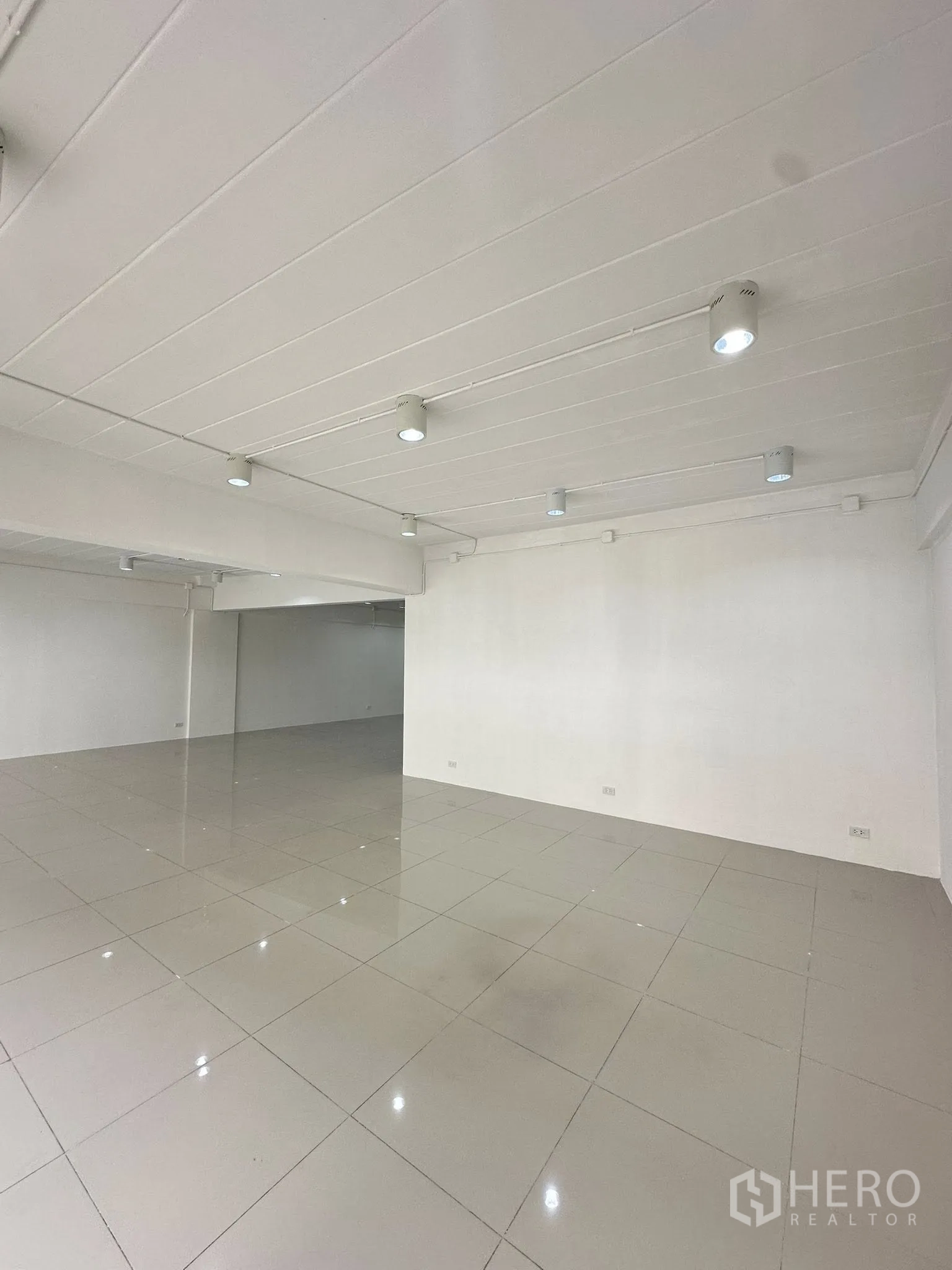 Office Space for rent in Watthana, Bangkok - Open office zone featuring track lighting on a white ceiling and smooth tiles.