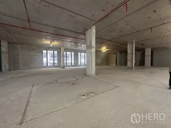 Retail Space for rent in Watthana, Bangkok - Shell‑and‑core retail space showing exposed sprinkler pipes, support pillars and multiple windows.