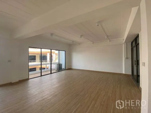 Office Space for rent in Watthana, Bangkok - Spacious 80 sqm office corner showing large windows, balcony access, and a white ceiling with track lights.