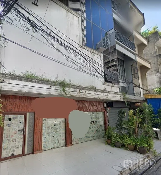 店屋 出租或出售在Khlong Toei, Bangkok - 店屋外立面，带瓷砖前院、贴报纸的玻璃门、盆栽与上方电线，都市曼谷街景。