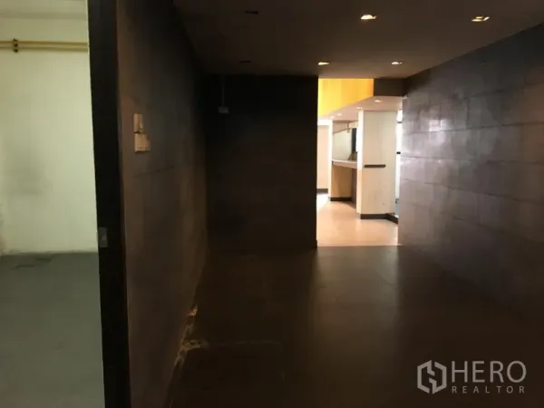 Retail Space for rent in Khlong Toei, Bangkok - Dim hallway with dark tiles and recessed lighting leading to the main retail area.
