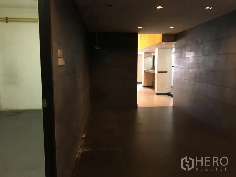 Retail Space for rent in Khlong Toei, Bangkok - Dim hallway with dark tiles and recessed lighting leading to the main retail area.