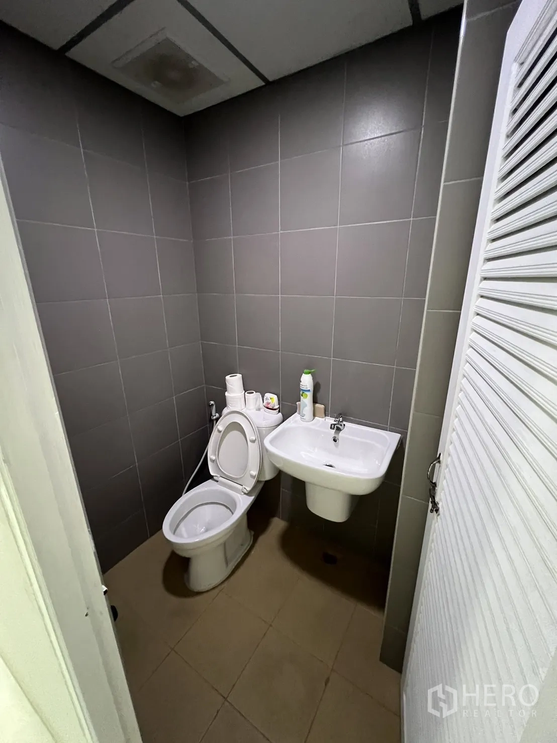 Shophouse for rent or sale in Watthana, Bangkok - Gray-tiled restroom with beige floor and compact layout.