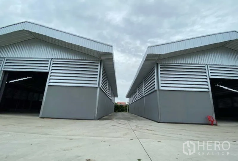 工厂 出租在Pathum Thani - 两栋平行仓厂建筑，配大型卷帘门与宽敞卡车通道，坐落于巴吞他尼工业用地内。