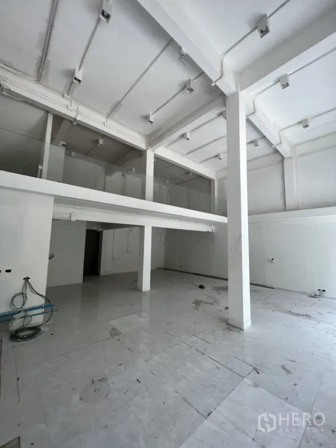Shophouse for rent in Watthana, Bangkok - Double-height ground floor of shophouse with white columns, mezzanine and tiled floor.