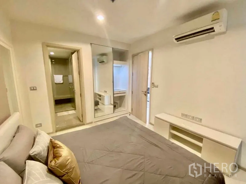 Condominium for rent in Khlong Toei, Bangkok - Bedroom with mirrored wardrobe, dressing nook, air-conditioning and doorway to the bathroom.
