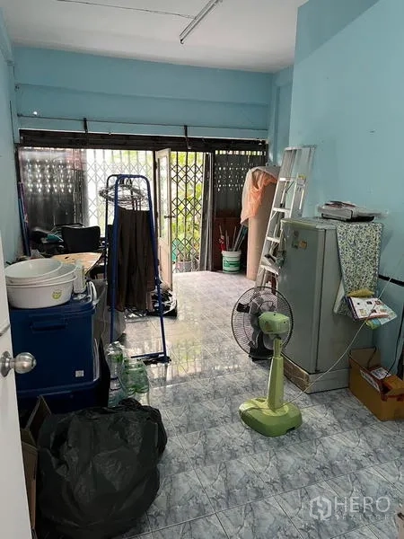 店屋 出租在Khlong Toei, Bangkok - 临街层商铺房间，蓝色墙面、瓷砖地面与金属栅栏门，适合店面或仓储。