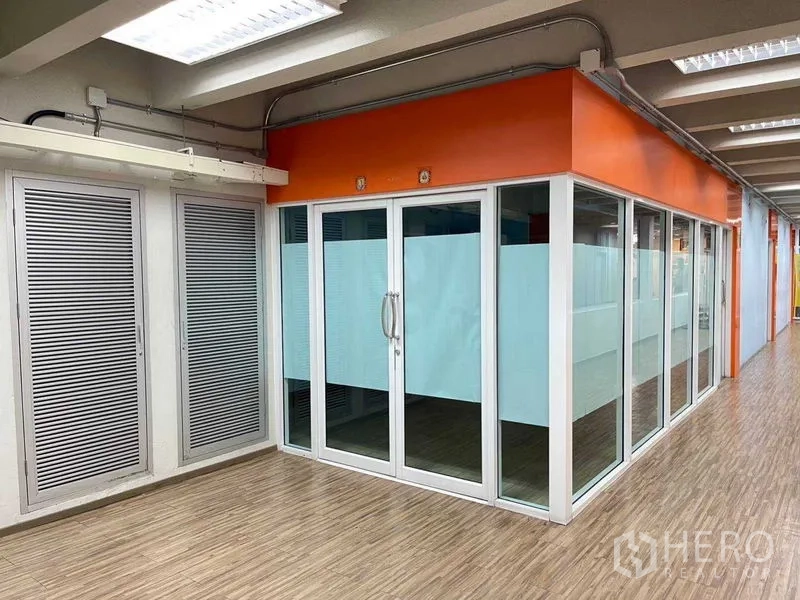 Office Space for rent in Ratchathewi, Bangkok - Corner glass-partitioned office with orange accent, frosted panels and wood-look floor under bright strip lights.