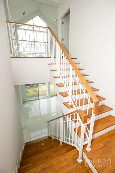 Detached House for rent or sale in Lam Luk Ka, Pathum Thani - Staircase with wooden treads and white balustrade leading to the ground floor.