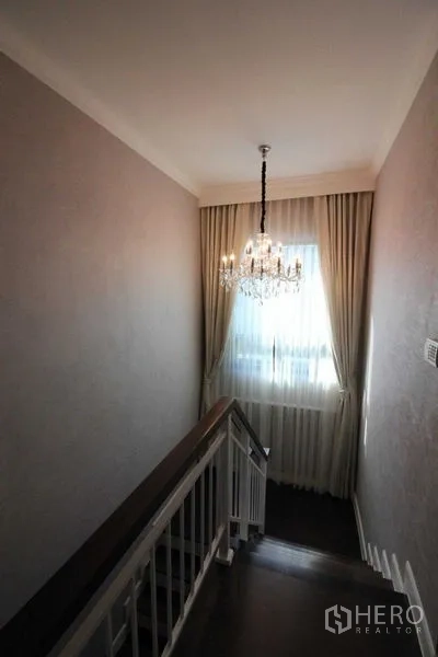 Detached House for rent in Prawet, Bangkok - Staircase landing with a crystal chandelier and full-height drapes.