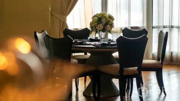 Condominium for rent in Khlong Toei, Bangkok - Round dining table set for six beside bright windows and flowing drapes.