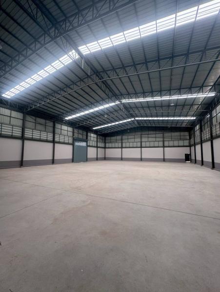 Factory for sale in Mueang Samut Sakhon, Samut Sakhon - Open warehouse floor with curved roof, skylights and wide roller door.