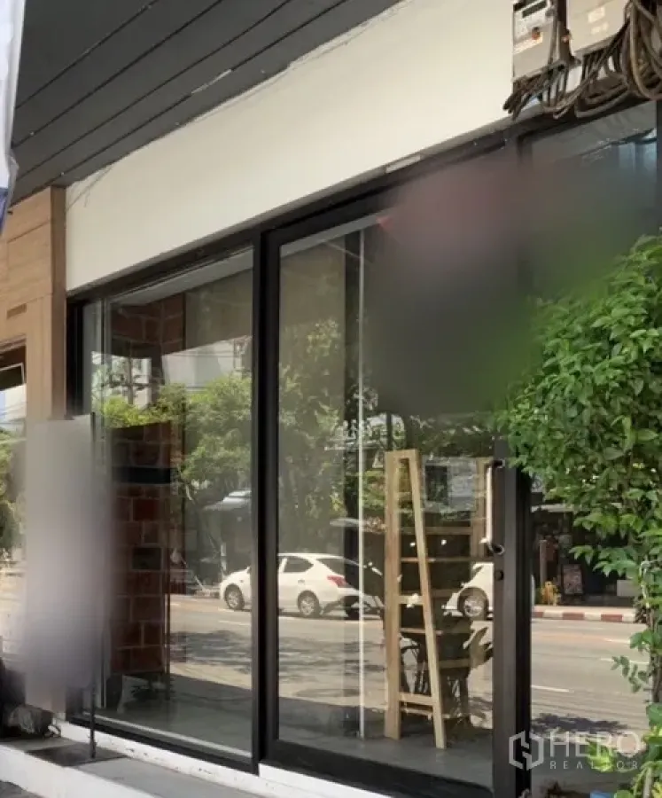 店屋 出租在Watthana, Bangkok - 临街玻璃门面，宽幅展示窗与绿植。