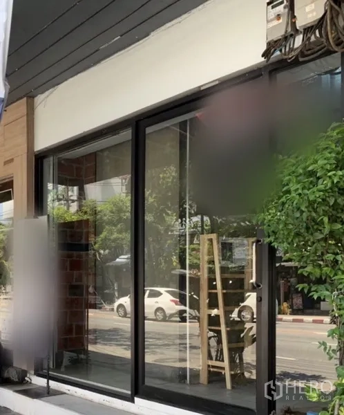 店屋 出租在Watthana, Bangkok - 临街玻璃门面，宽幅展示窗与绿植。