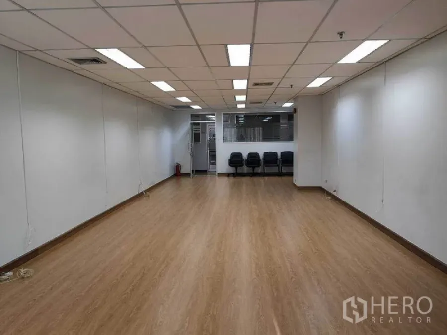Office Space for rent in Watthana, Bangkok - Wide shot toward the entrance of an open office with laminate floors, ceiling air-conditioning, and seating by a glass partition.