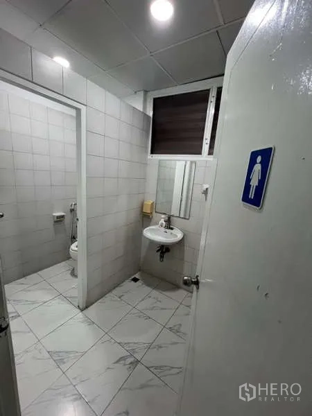 Shophouse for rent or sale in Khlong Toei, Bangkok - Simple tiled restroom with two stalls, sink and mirror.