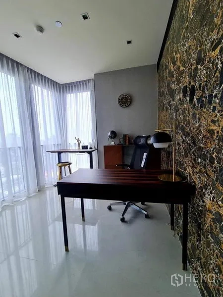 Condominium for rent in Khlong Toei, Bangkok - Bright study with marble feature wall and corner windows with sheer curtains.