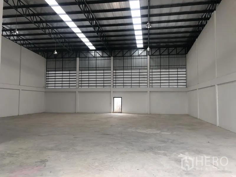 工厂 出租在Sai Noi, Nonthaburi - 大型仓库大厅，钢结构高屋顶，采光板与后部安全门。