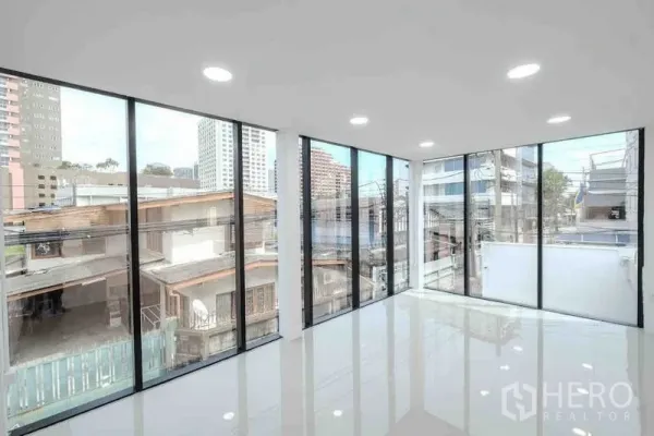Standalone for rent or sale in Bang Na, Bangkok - Corner office with panoramic glass walls and neighborhood city views.
