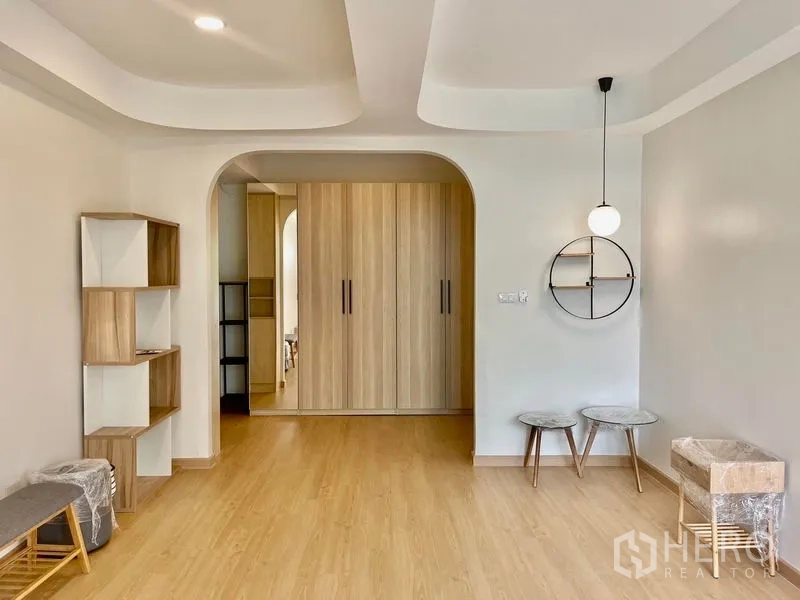 Townhouse for rent in Khlong Toei, Bangkok - Bedroom featuring arched doorway to wardrobe, pendant light and built-in shelves.