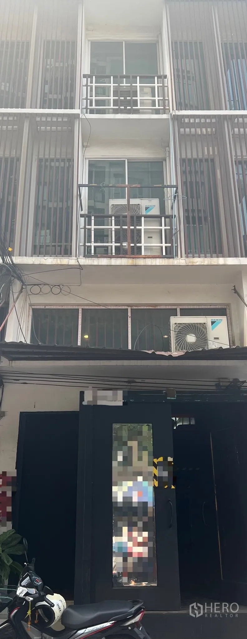 Shophouse for rent in Khlong Toei, Bangkok - Street‑front multi‑storey shophouse with balconies, sliding windows, vertical screens and exterior AC units.
