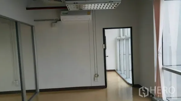 Office Space for rent in Khlong Toei, Bangkok - Bright office room with large window, doorway to corridor, and built-in air conditioning.