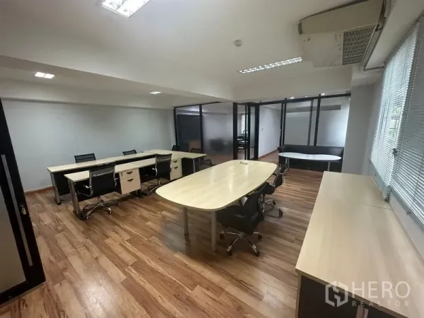 Office Space for rent in Khlong Toei, Bangkok - Open-plan office with wood flooring, long desks and swivel chairs, frosted-glass partitions, and ceiling lights.