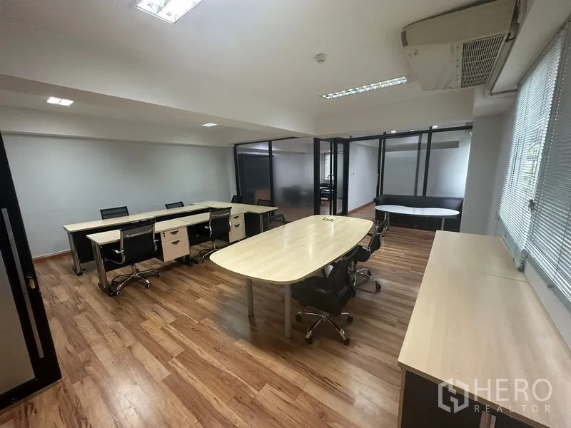 Office Space for rent in Khlong Toei, Bangkok - Open-plan office with wood flooring, long desks and swivel chairs, frosted-glass partitions, and ceiling lights.
