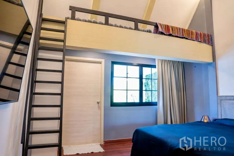 Townhouse for rent in Khlong Toei, Bangkok - Bedroom with mezzanine loft, metal ladder and large window with drapes.