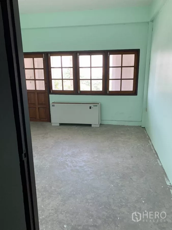 Shophouse for rent in Suan Luang, Bangkok - Room with large wood-framed windows and door, concrete floor and wall unit.