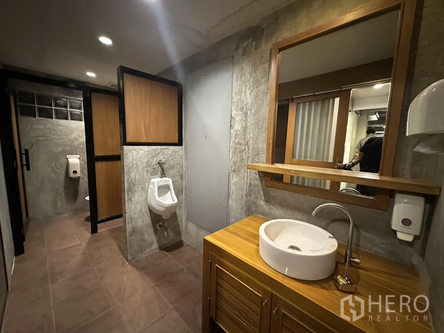 Retail Space for rent in Watthana, Bangkok - Modern restroom with urinal, stone‑look walls, wooden vanity, round basin, and mirror.