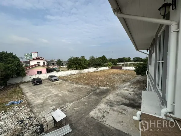 Home Office for rent - Upper-floor view over a concrete parking area with cars inside a walled compound.