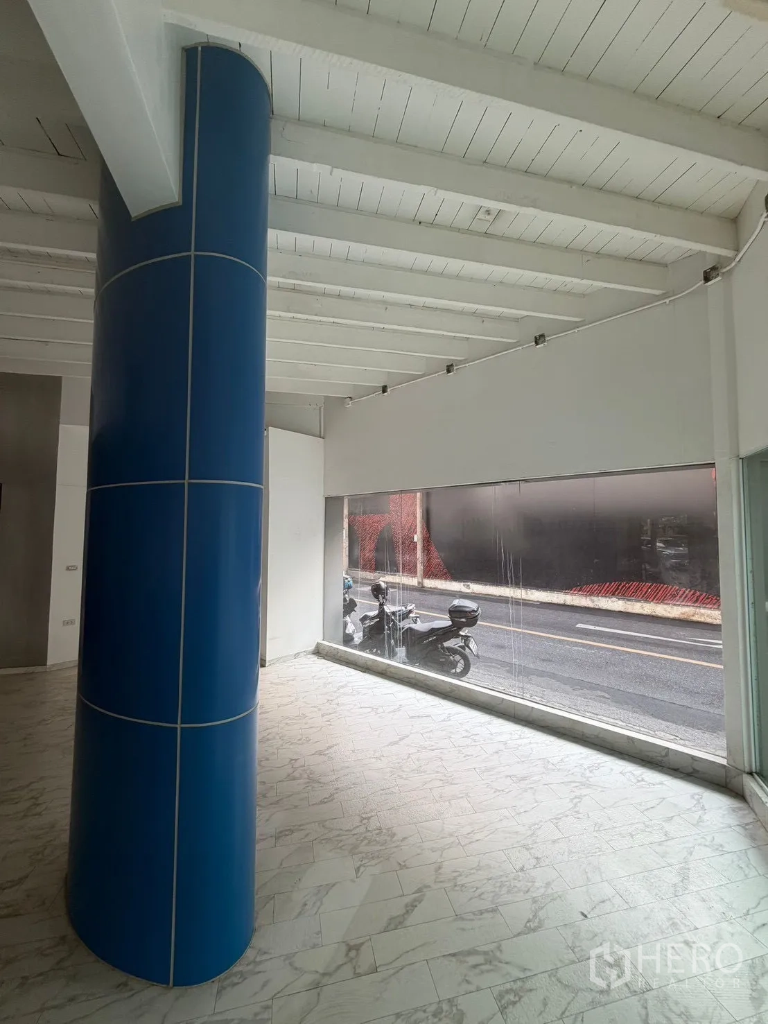 ตึกแถว for rent in Watthana, Bangkok - มุมภายในมีเสาสีน้ำเงิน เพดานคานไม้สีขาว และกระจกเต็มบาน.