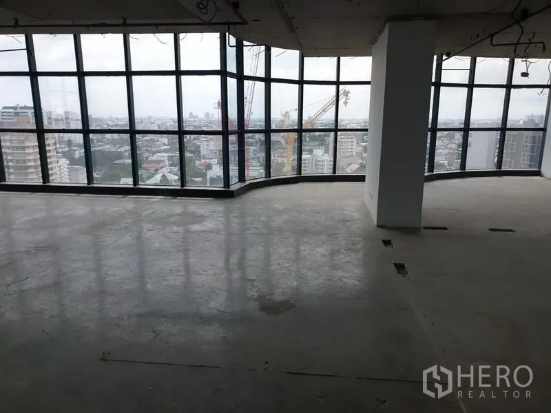 Office Space for rent in Watthana, Bangkok - Open-plan office space with curved glass façade overlooking the Ekkamai cityscape.